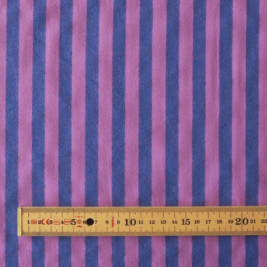 Purple and blue vertically striped fabric with a wooden ruler at the bottom showing the scale of the stripes.