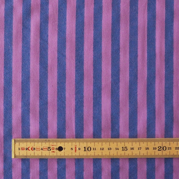 Purple and blue vertically striped fabric with a wooden ruler at the bottom showing the scale of the stripes.