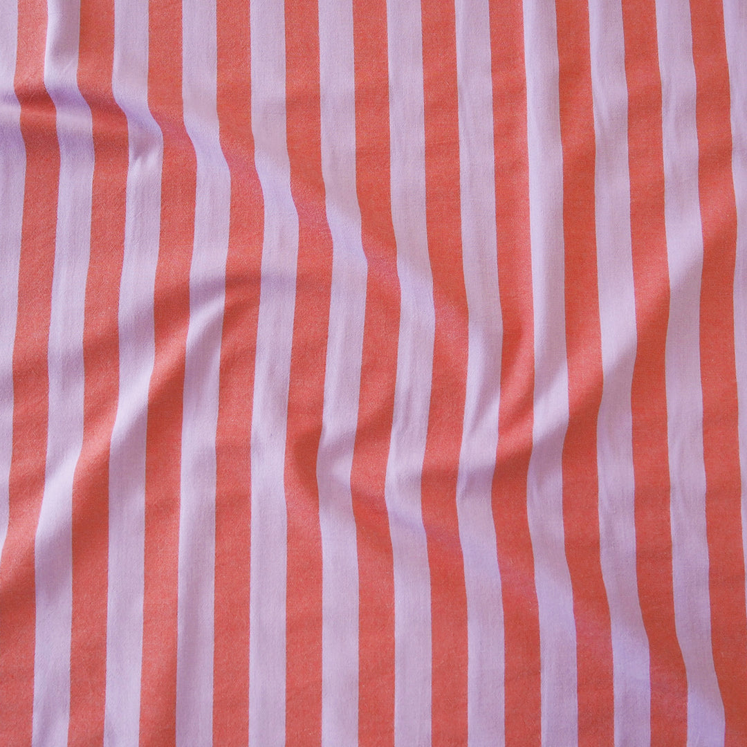 A close-up of a striped fabric with alternating vertical stripes of coral orange and light purple, showing soft folds and texture.