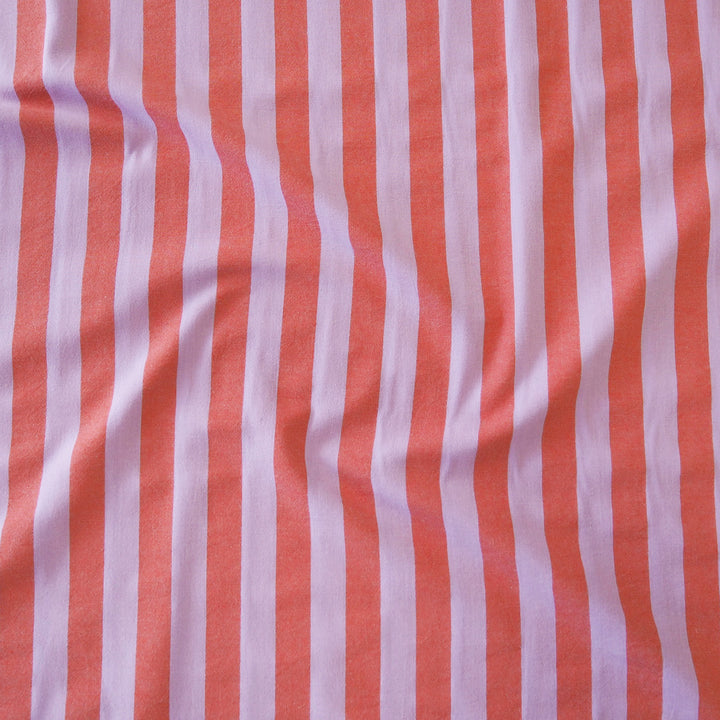 A close-up of a striped fabric with alternating vertical stripes of coral orange and light purple, showing soft folds and texture.