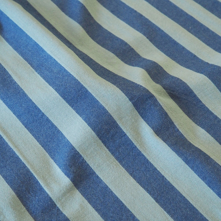 A close-up of striped fabric with alternating wide and narrow diagonal stripes in muted navy and teal.
