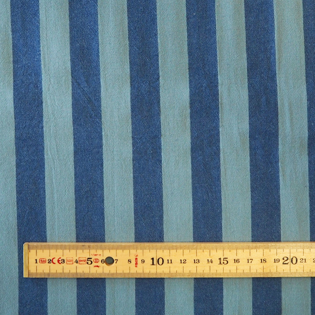 Navy and teal vertical striped fabric with a wooden ruler at the bottom showing the scale of the stripes.