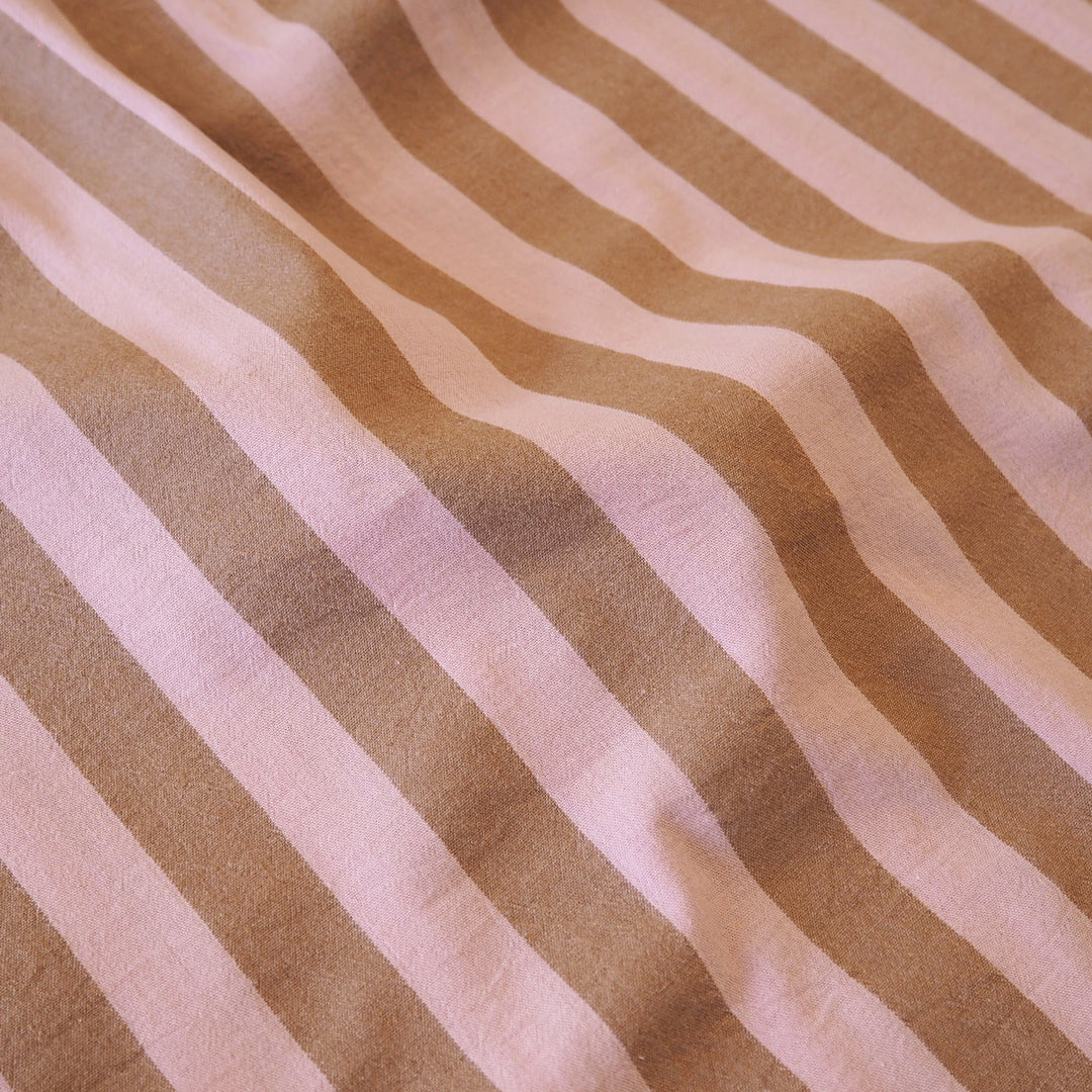 A close-up of a striped fabric with alternating warm tan and light pinkish-beige vertical stripes, showing a soft woven texture.