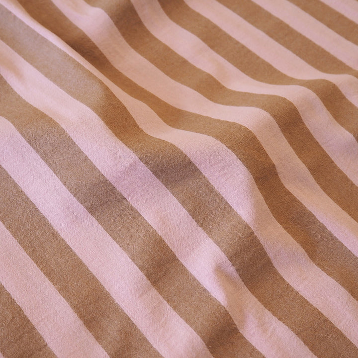 A close-up of a striped fabric with alternating warm tan and light pinkish-beige vertical stripes, showing a soft woven texture.