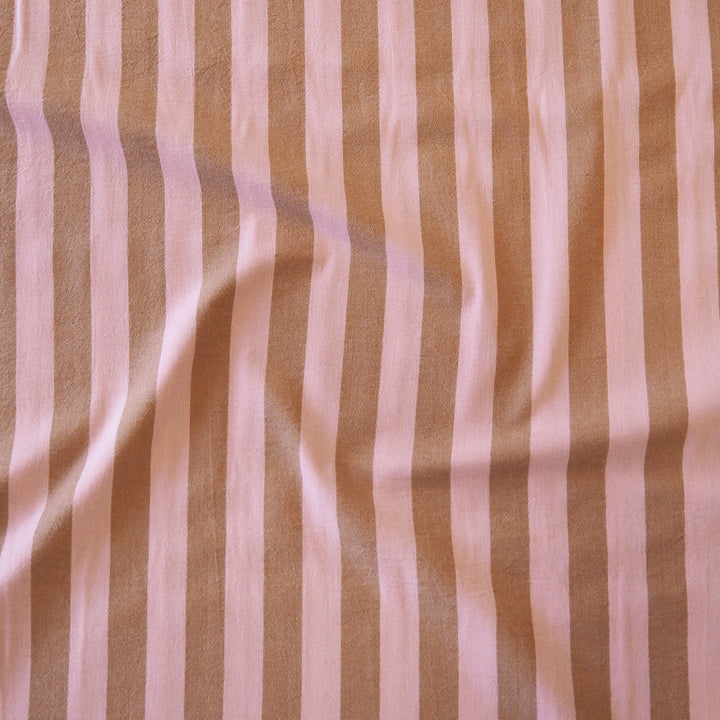A close-up of a striped fabric with alternating vertical bands of warm tan and soft light pink, showing a slightly textured woven surface with gentle folds.