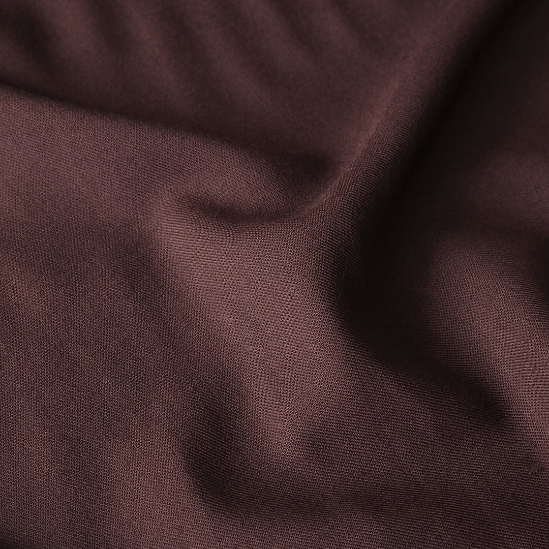 A close-up of draped dark brown fabric with a fine ribbed texture and soft folds.