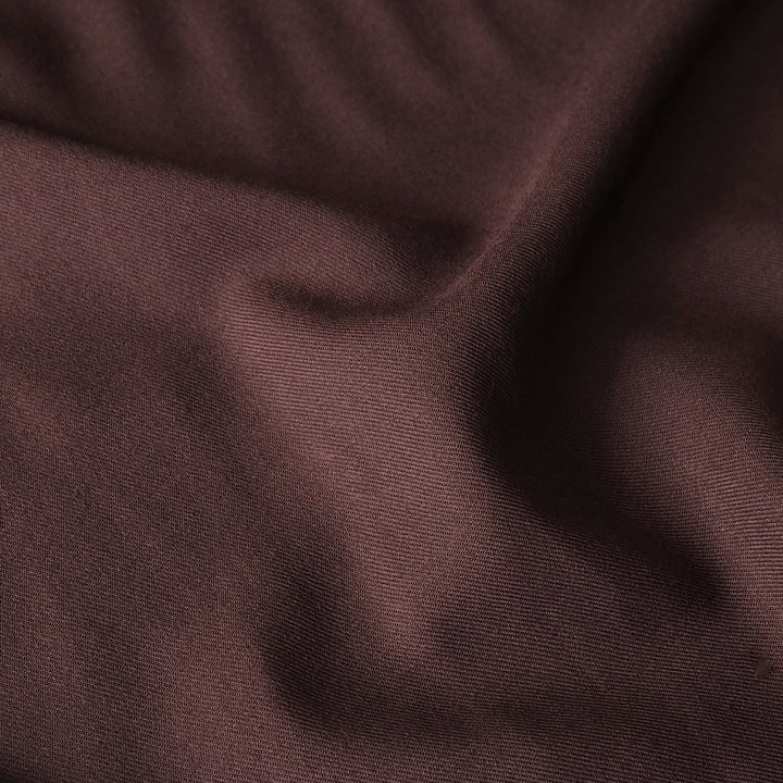 A close-up of draped dark brown fabric with a fine ribbed texture and soft folds.