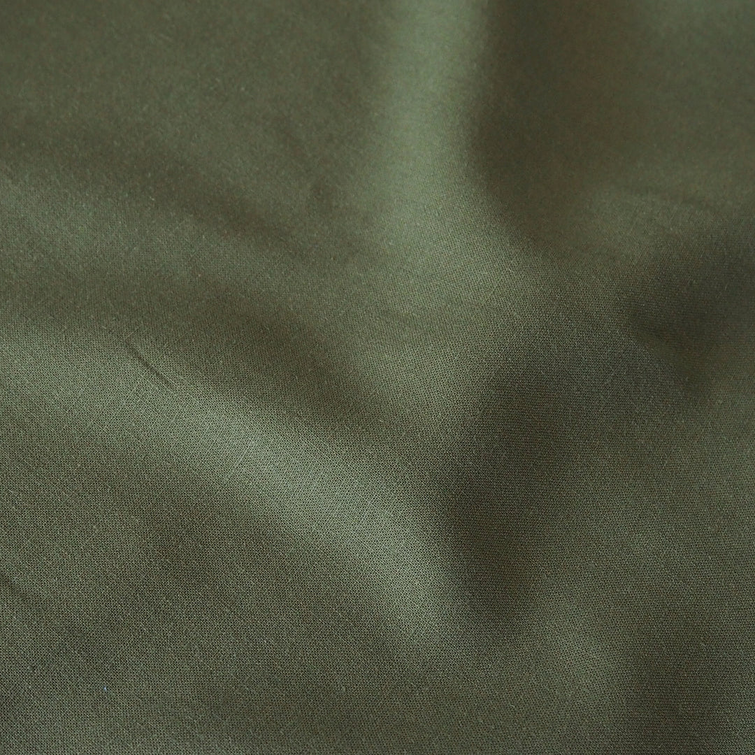A close-up of draped olive green fabric with soft folds and a matte texture.