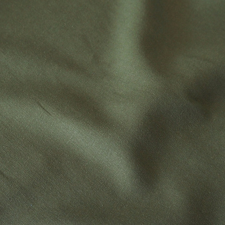 A close-up of draped olive green fabric with soft folds and a matte texture.