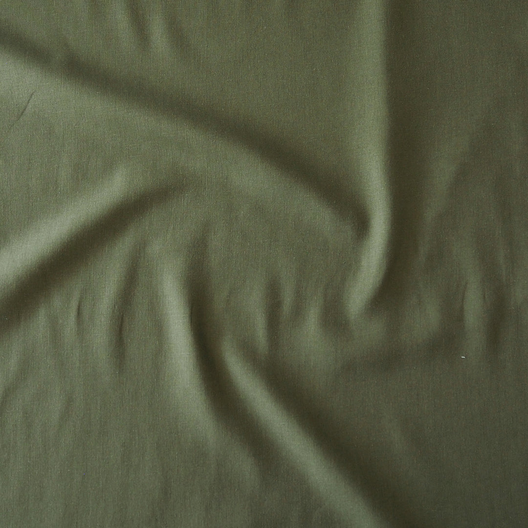 A close-up of draped olive green fabric with soft folds and a matte texture.