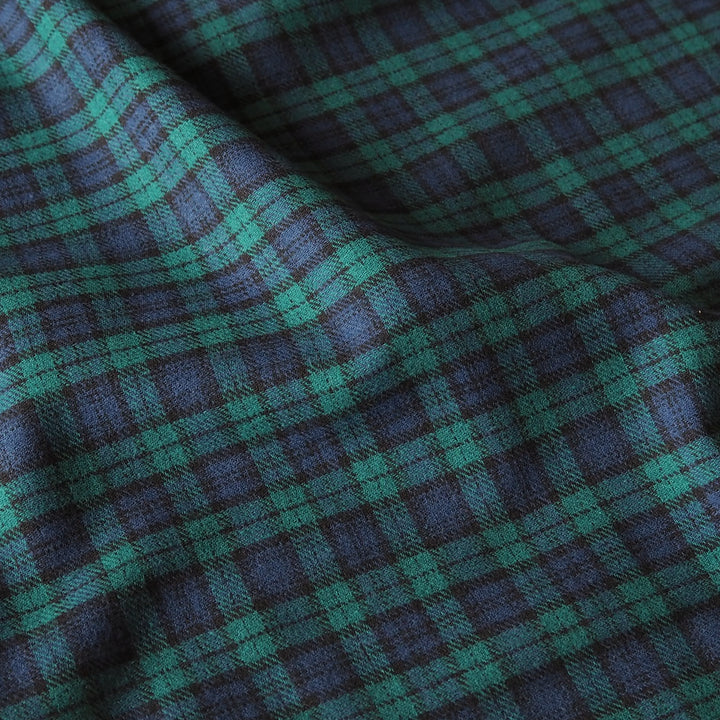 A close-up of a plaid fabric with a woven texture, featuring a pattern of teal green and dark navy blue.