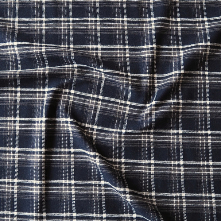 A close-up of draped navy blue fabric with a white and light gray plaid pattern.