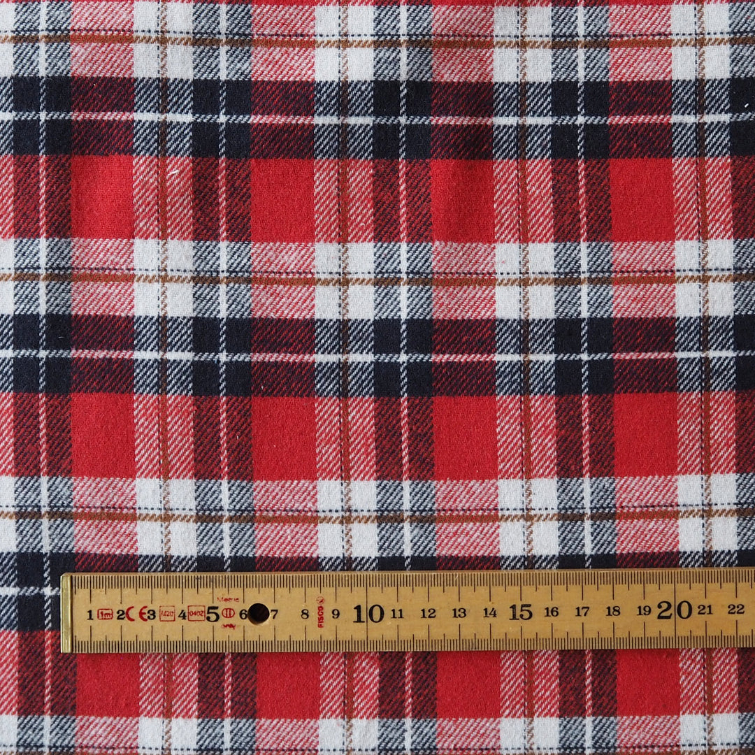 Red, white, and black plaid fabric shown with a wooden ruler at the bottom to indicate scale.