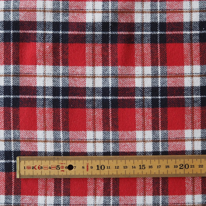 Red, white, and black plaid fabric shown with a wooden ruler at the bottom to indicate scale.
