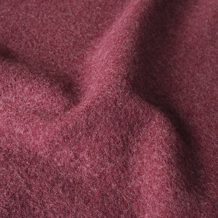 A close-up of draped, fuzzy fabric in a dusty rose or mauve color, showing its soft texture and fine fibers.