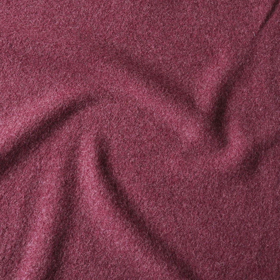 A close-up of draped, textured fabric in a deep wine or burgundy shade, filling the entire frame.