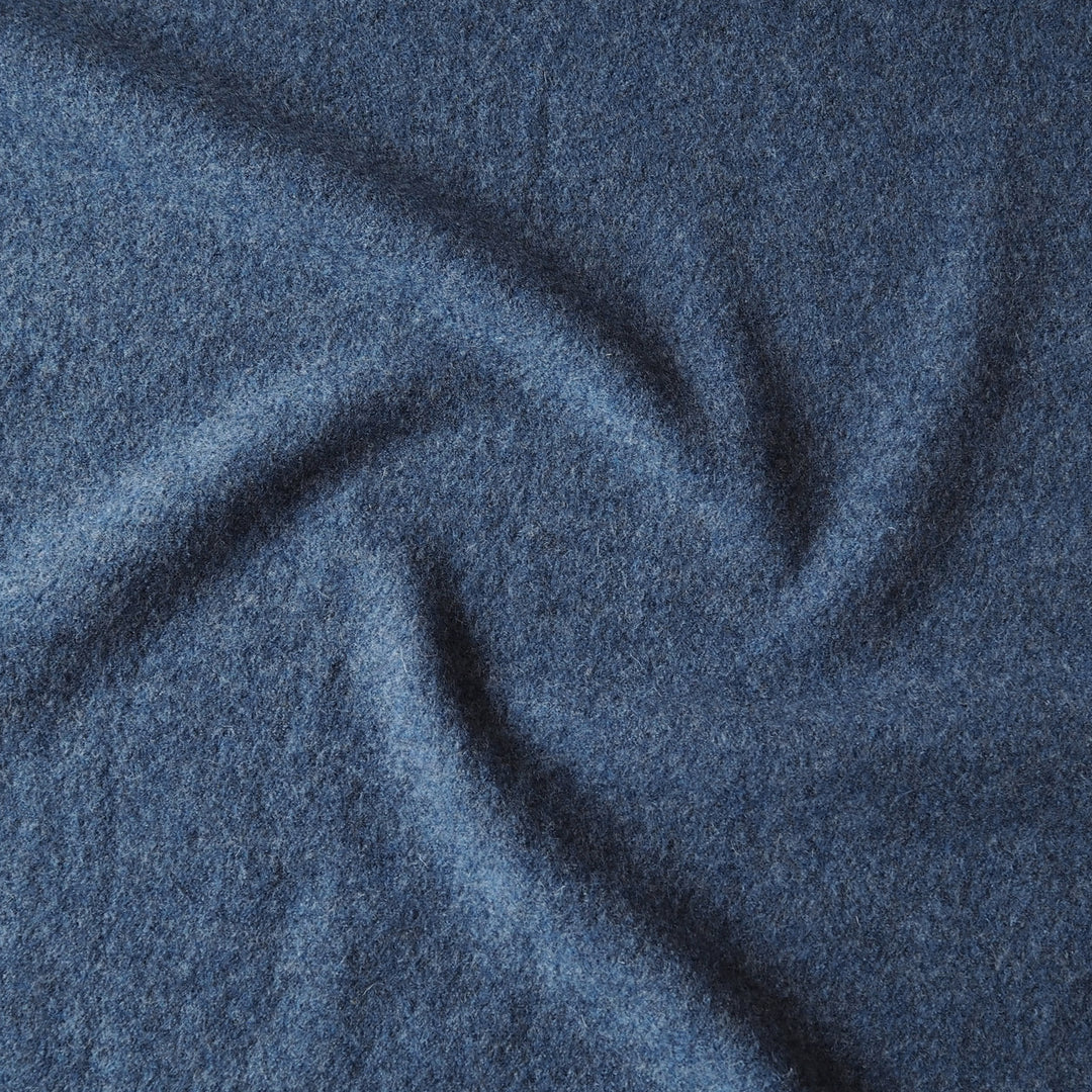 A close-up of textured blue fabric with soft folds and a heathered, slightly nubby surface.
