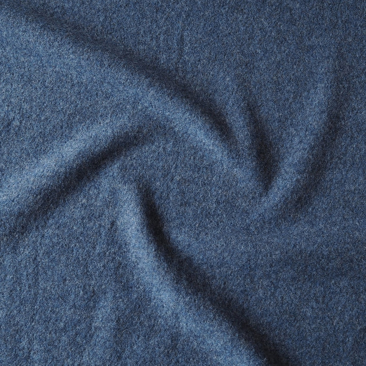 A close-up of textured blue fabric with soft folds and a heathered, slightly nubby surface.