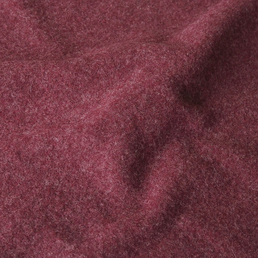 A close-up of textured, heathered burgundy fabric with soft folds and a fuzzy, wool-like surface.
