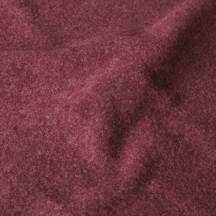 A close-up of textured, heathered burgundy fabric with soft folds and a fuzzy, wool-like surface.