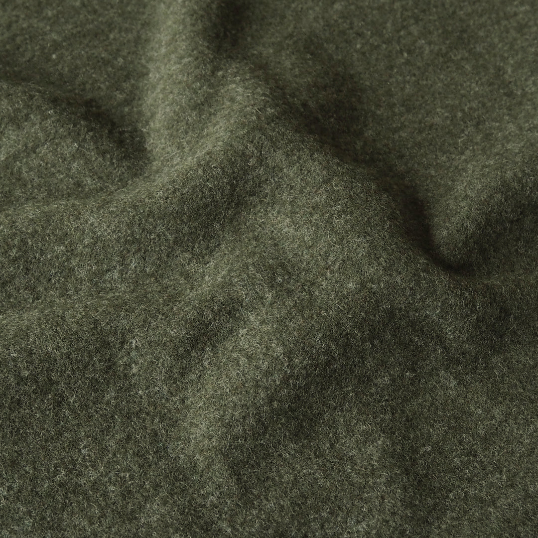 A close-up of dark olive green textured fabric with soft folds and a heathered, wool-like surface.