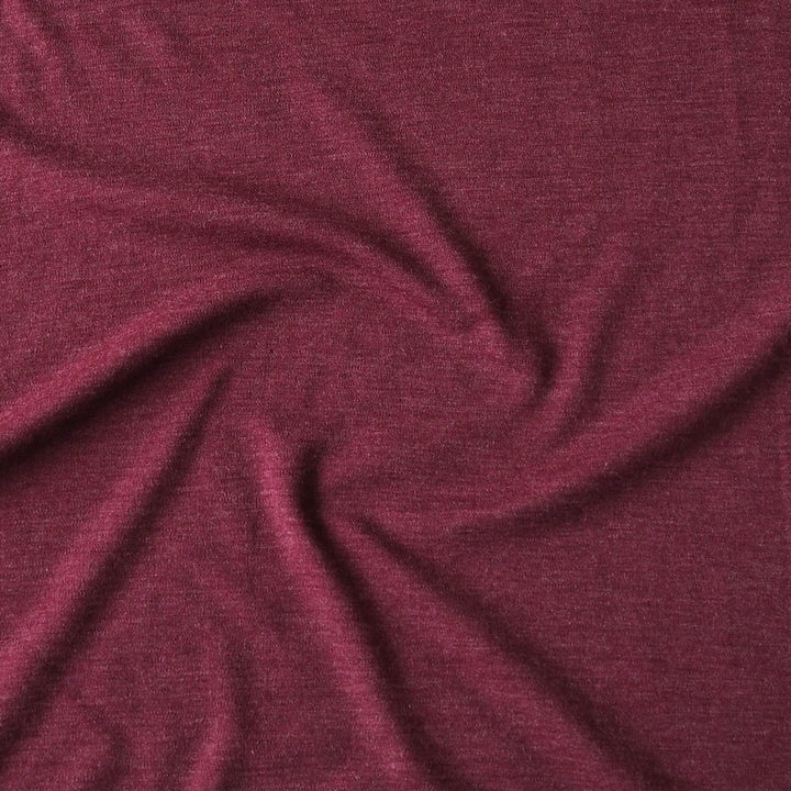 A close-up of draped heathered burgundy fabric with soft folds and a subtle textured weave.