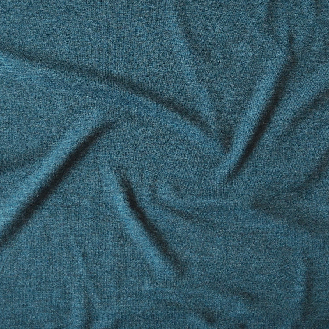 A close-up of textured heathered teal blue fabric with soft folds and wrinkles.