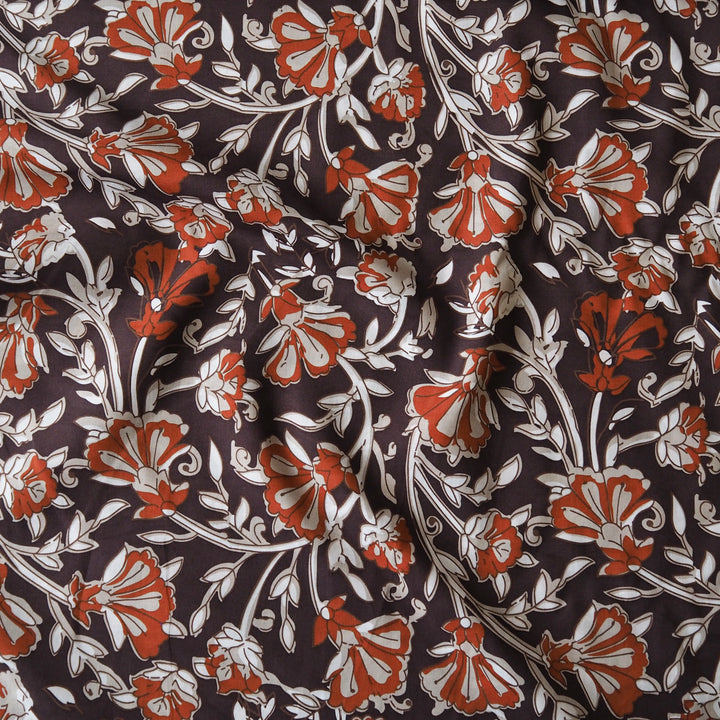 A close-up of a fabric pattern featuring stylized orange-red flowers and cream vines on a dark brown background.