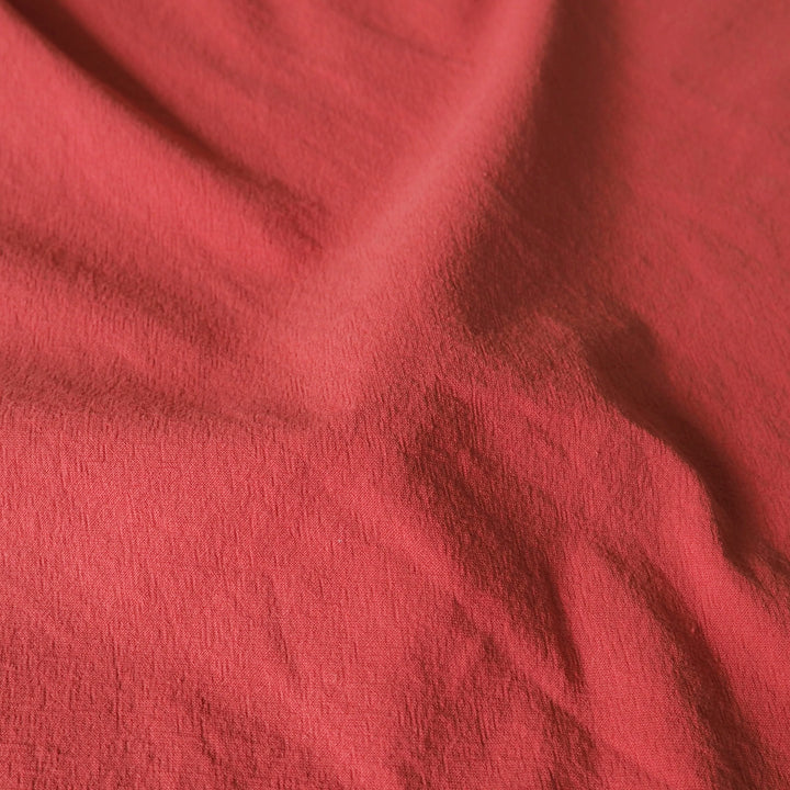 A close-up of draped coral pink fabric with a soft, textured surface.