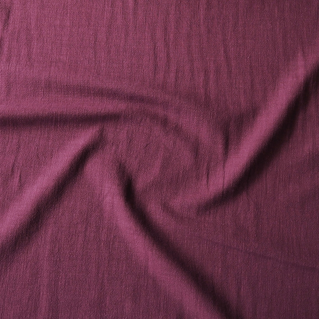 A close-up of draped mauve-purple fabric with a textured, slightly crinkled surface.