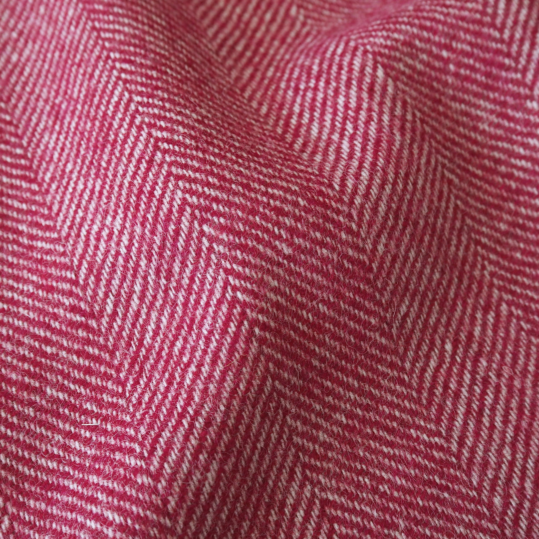 A close-up of a woven fabric with a pink and white herringbone pattern, showing the texture and weave details.