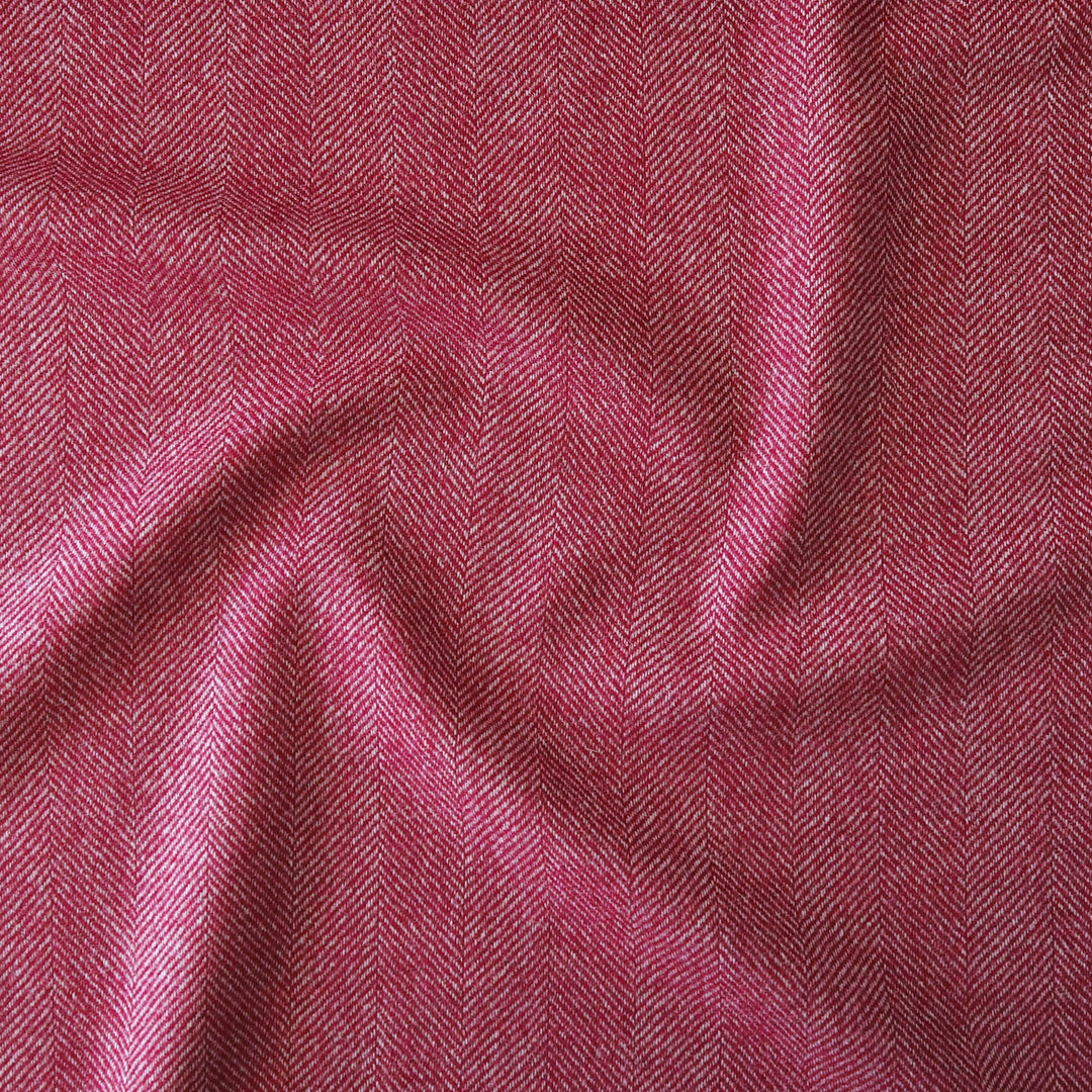 A close-up of draped fabric with a pink and red herringbone pattern, showing the texture and weave.