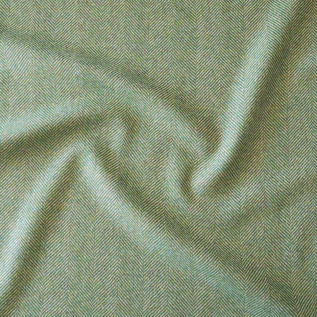 A close-up of draped fabric with a fine herringbone pattern in muted sage green and light gray tones.