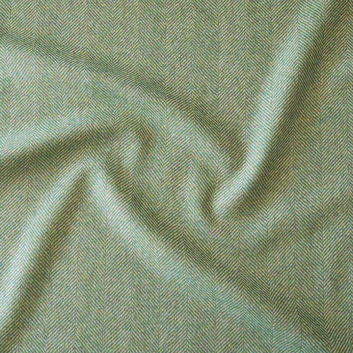A close-up of draped fabric with a fine herringbone pattern in muted sage green and light gray tones.
