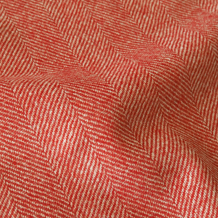 A close-up of a woven fabric with a red and off-white herringbone pattern, showing the texture and folds.