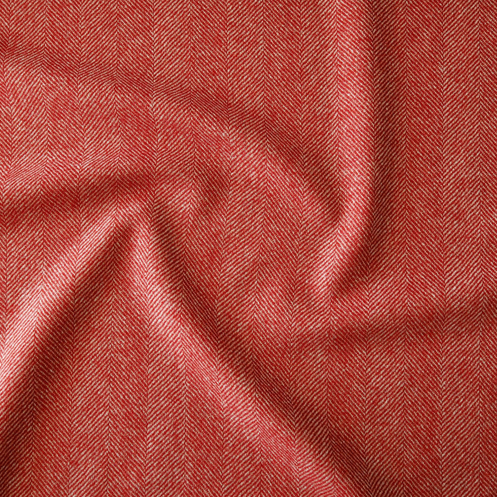 A close-up of textured fabric with a red and white herringbone pattern, shown with soft folds and shadows.