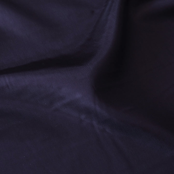 A close-up of dark navy blue fabric with soft folds and a smooth texture.
