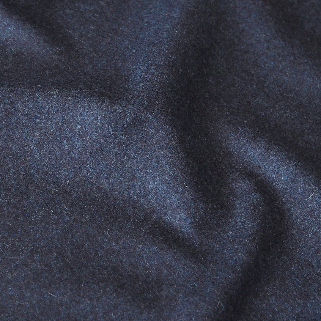 A close-up of dark navy blue textured fabric with soft folds and a slightly fuzzy, brushed surface.