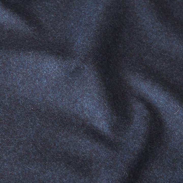 A close-up of dark navy blue textured fabric with soft folds and a slightly fuzzy, brushed surface.