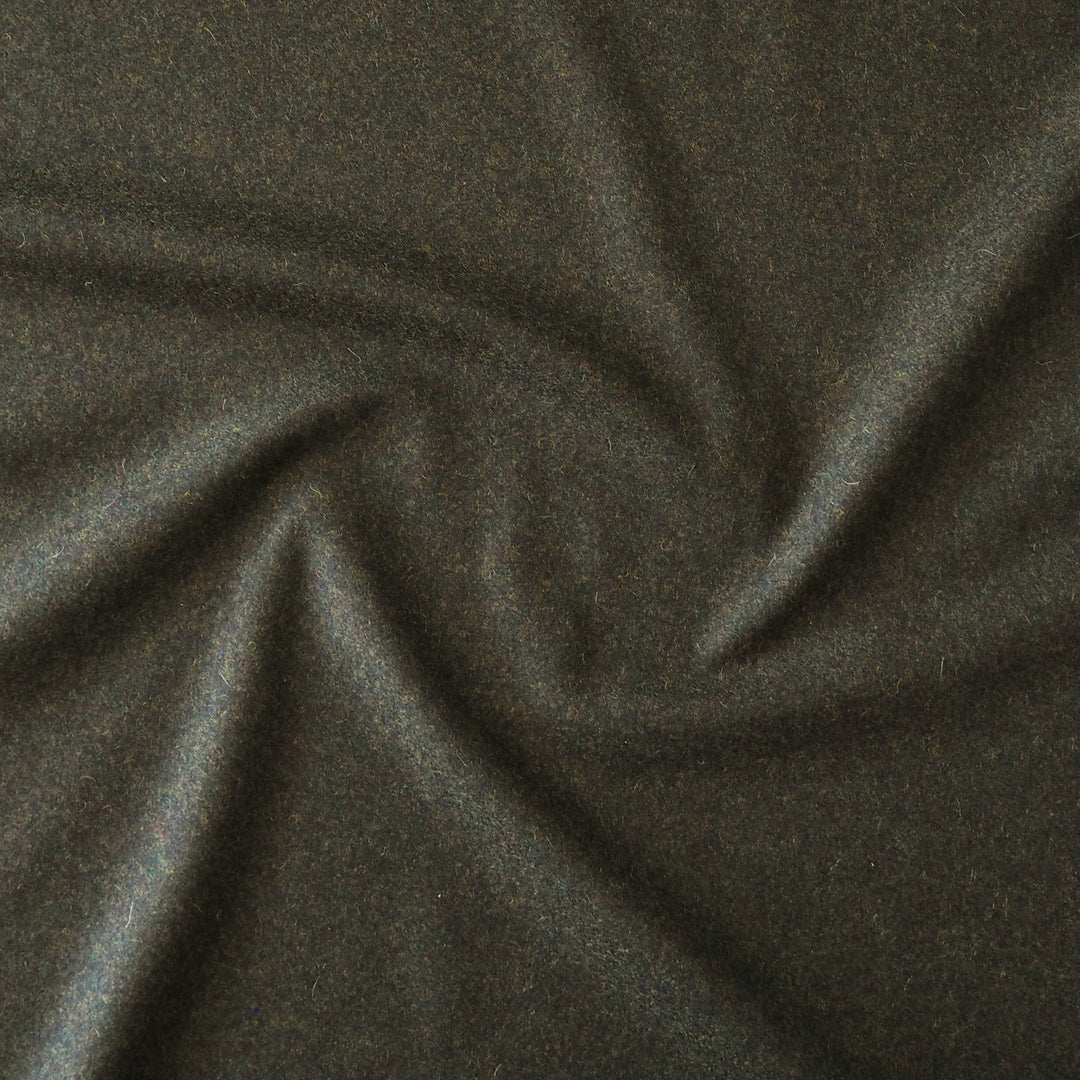 A close-up of dark charcoal green fabric with a soft, slightly textured surface, arranged in a gentle spiral drape.