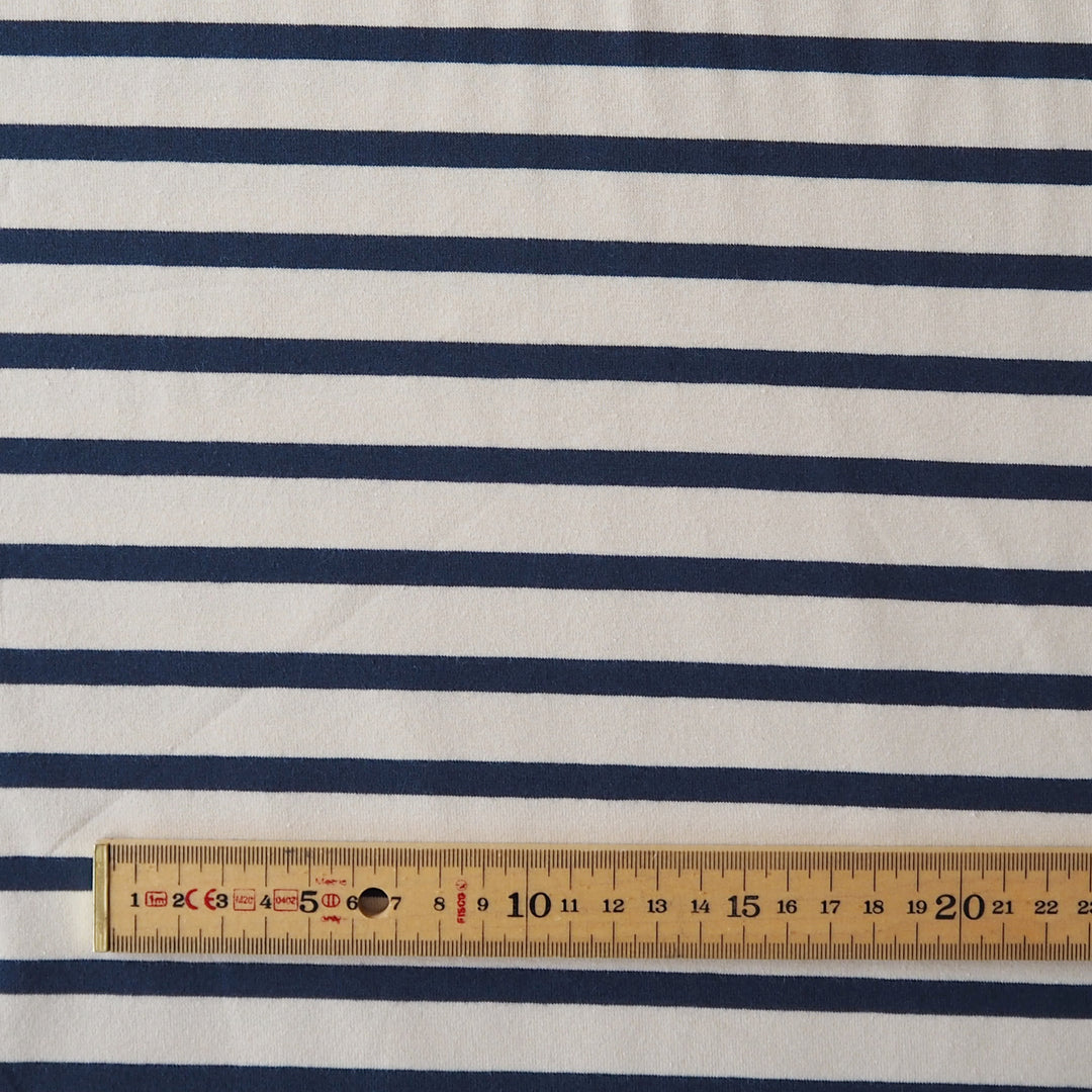 Navy blue and white striped fabric with a wooden ruler at the bottom showing the scale of the stripes.