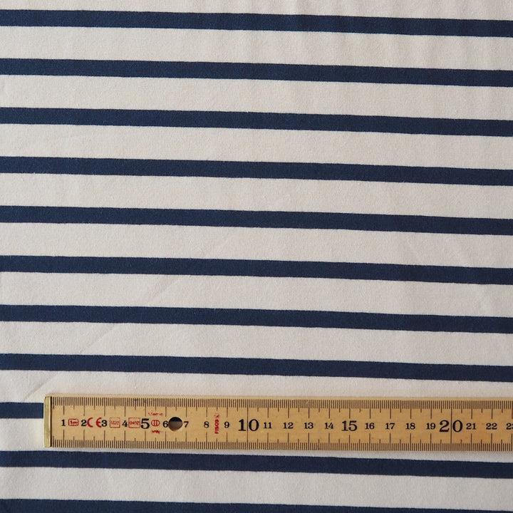 Navy blue and white striped fabric with a wooden ruler at the bottom showing the scale of the stripes.