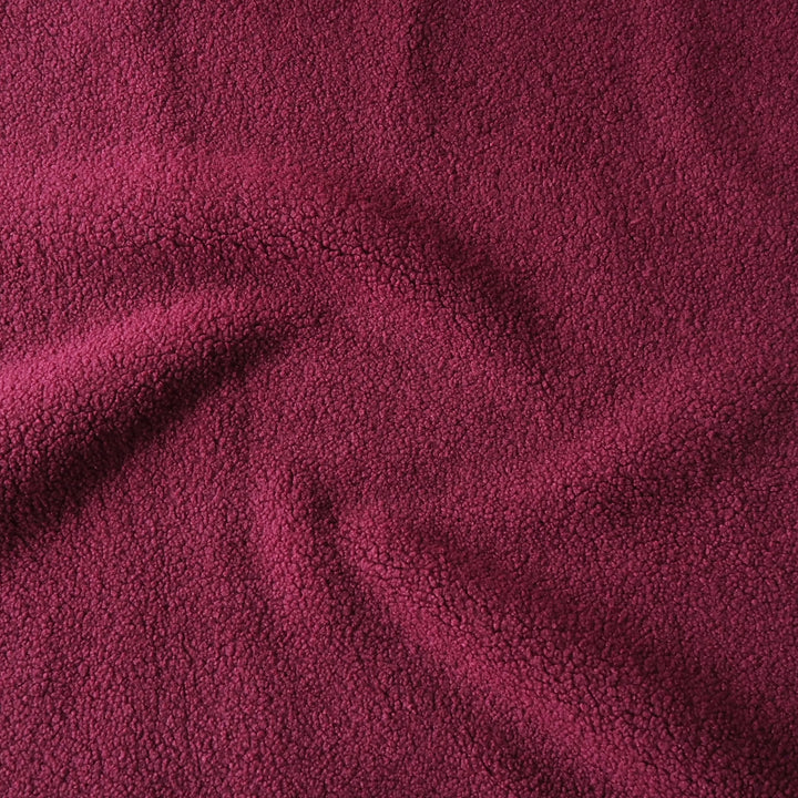 A close-up of textured plush fleece fabric in a deep red color, showing soft folds and a looped pile texture.