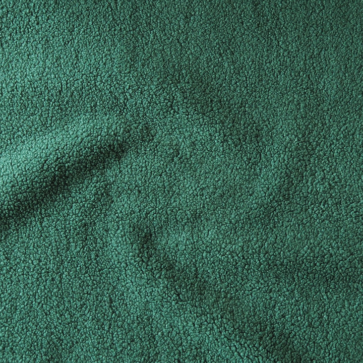 A close-up of a dark teal green textured fabric with a soft, nubby surface and gentle folds.