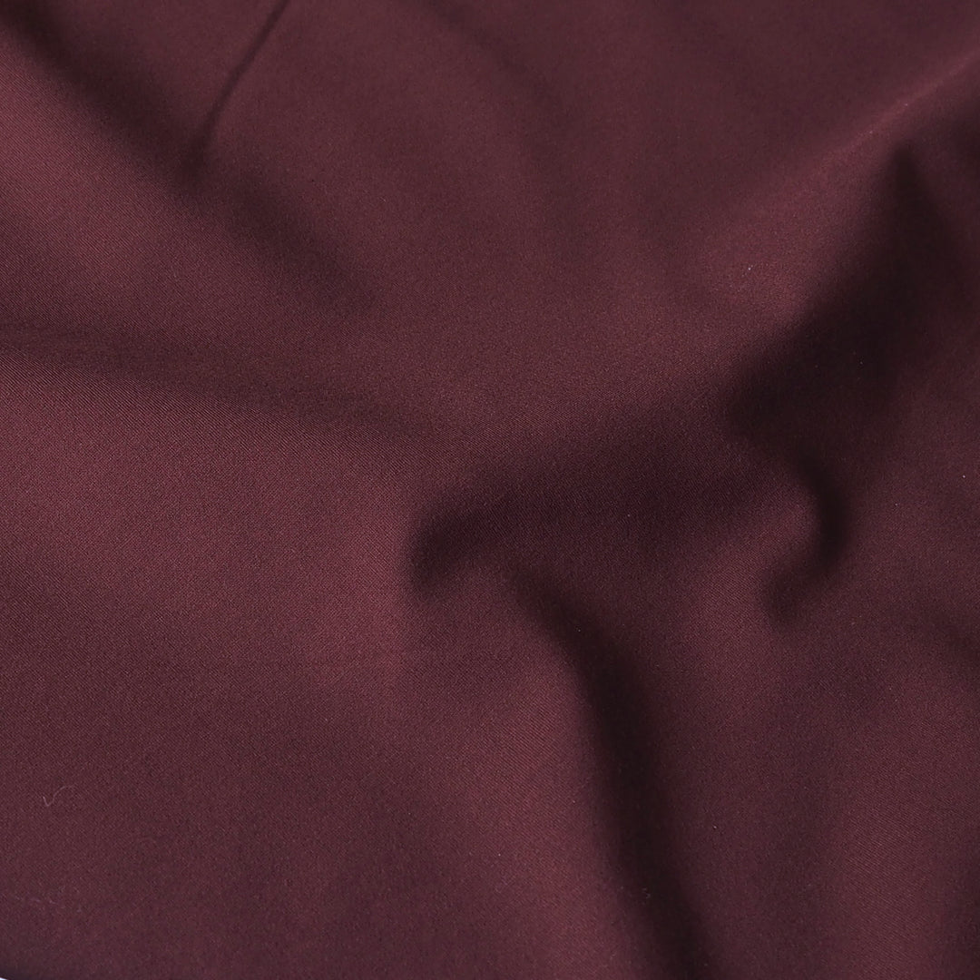 A close-up of draped burgundy fabric with soft folds and a subtle sheen.
