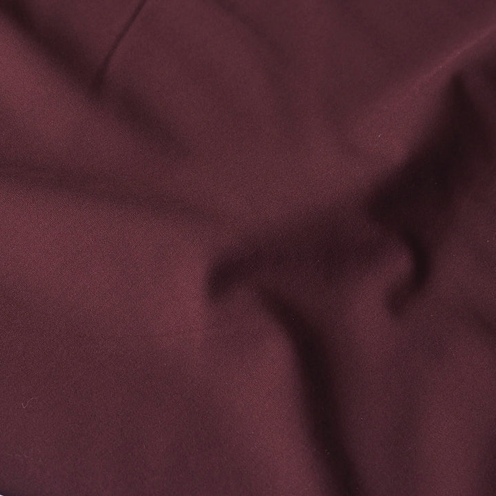 A close-up of draped burgundy fabric with soft folds and a subtle sheen.