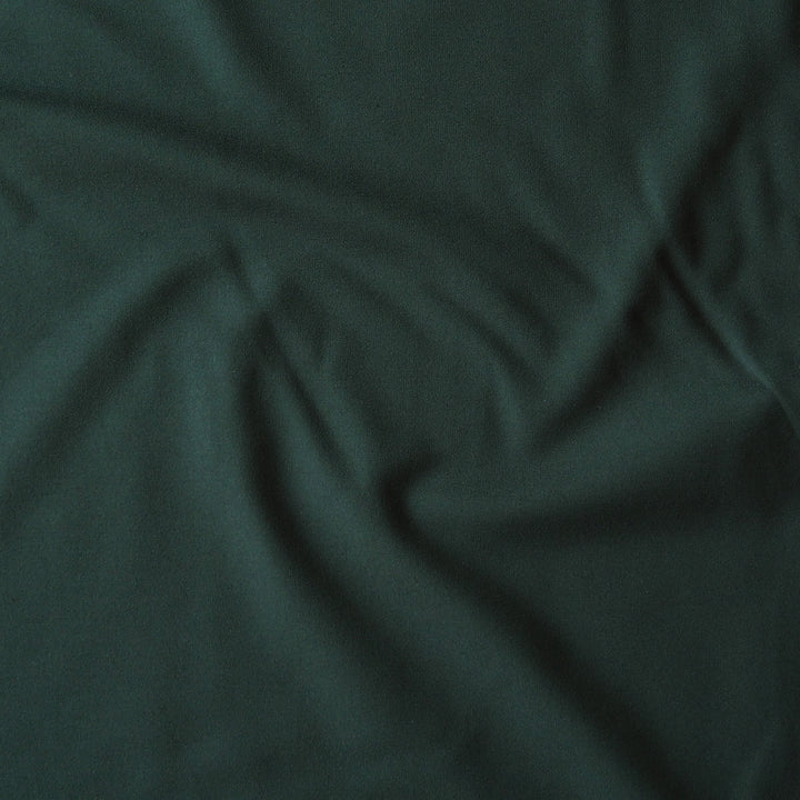 Dark forest green fabric with soft folds and a smooth texture filling the frame.