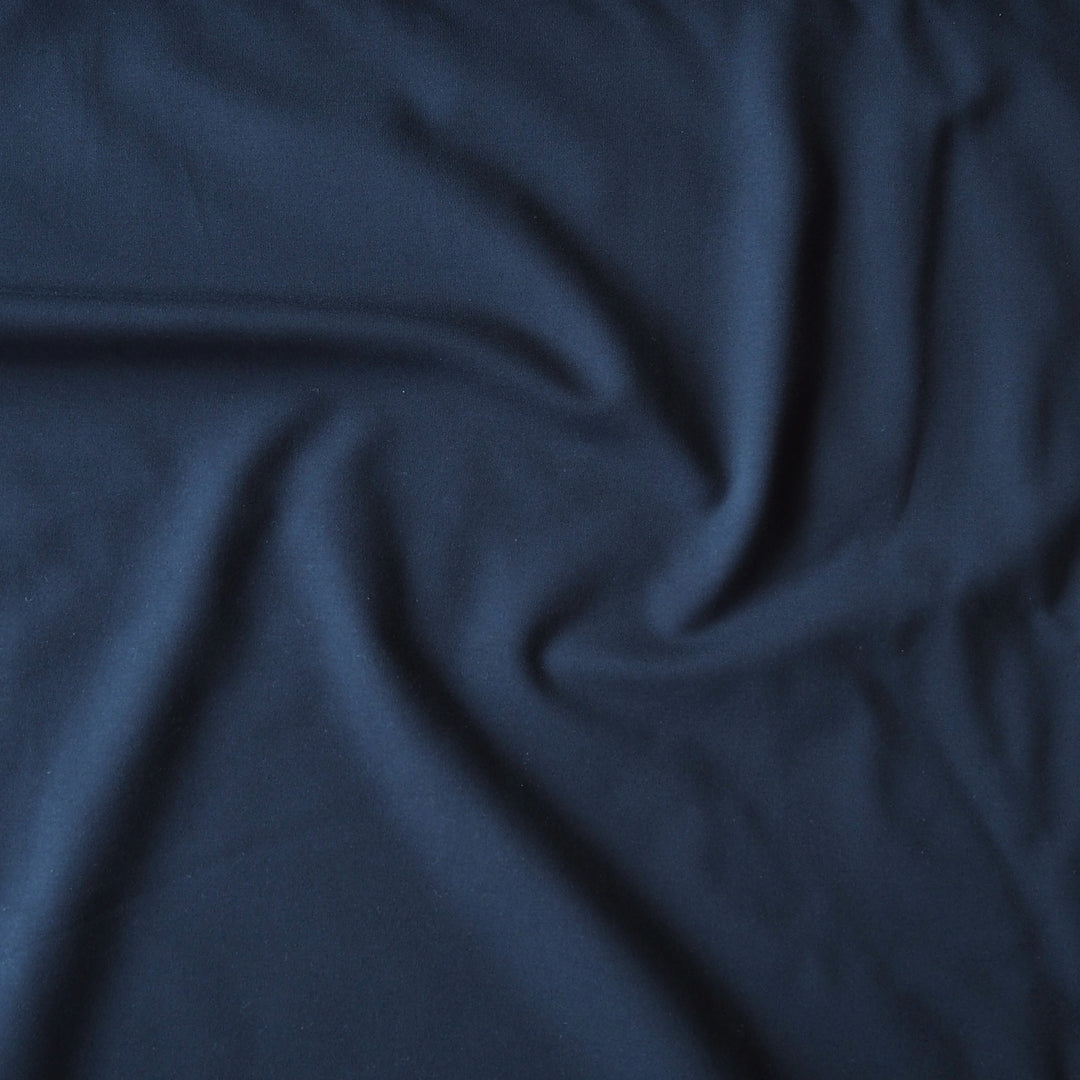 A close-up of draped navy blue fabric with soft folds and a smooth texture.