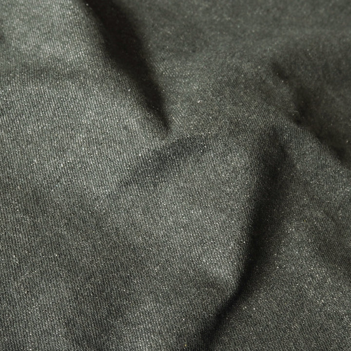 A close-up of dark charcoal gray fabric with a fine textured weave and soft folds.