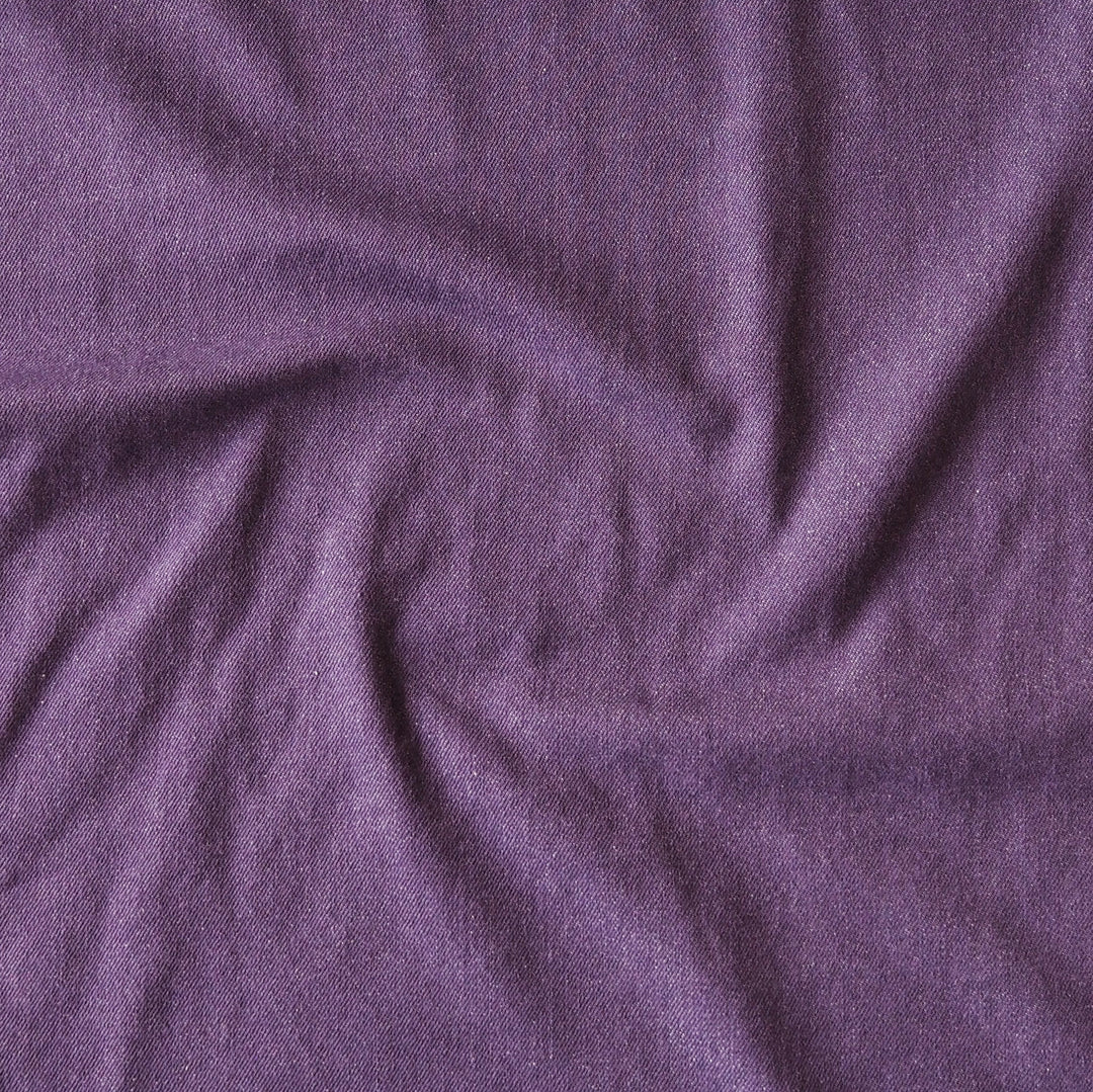 A close-up of draped purple fabric with a soft, slightly textured surface and gentle folds.
